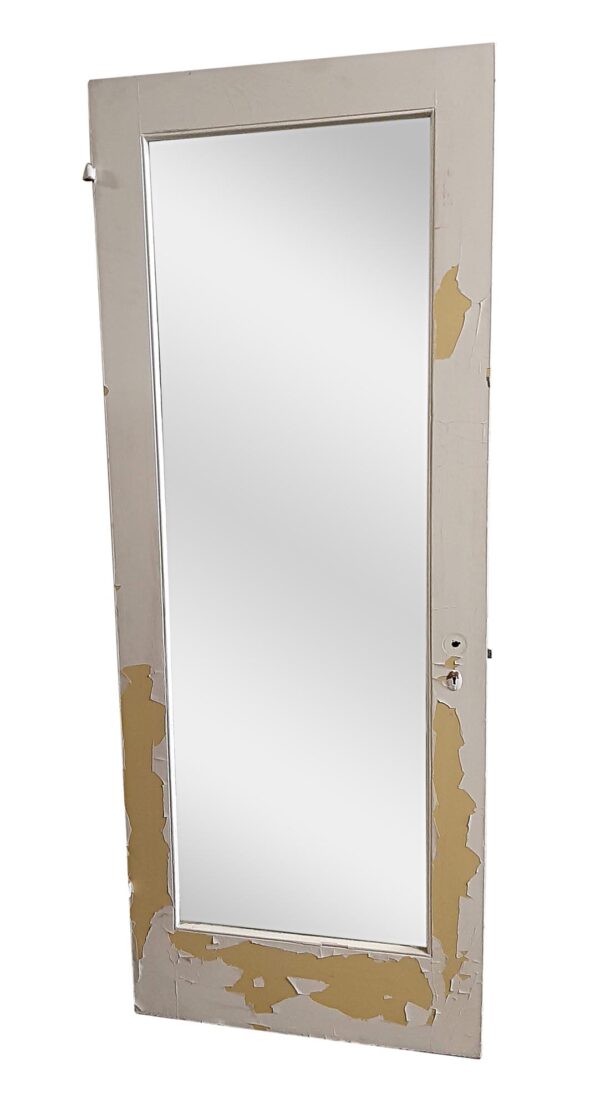White wooden closet door with a full-length mirrored panel and chipped painted finish.