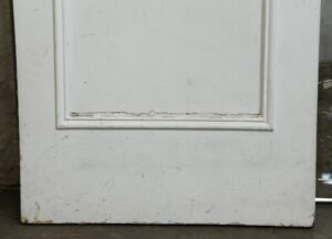 White mirrored closet door with one recessed panel and worn paint along the bottom edge.