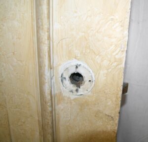 Close-up of a closet door showing a circular hardware opening on the tan wood side with the door edge visible.