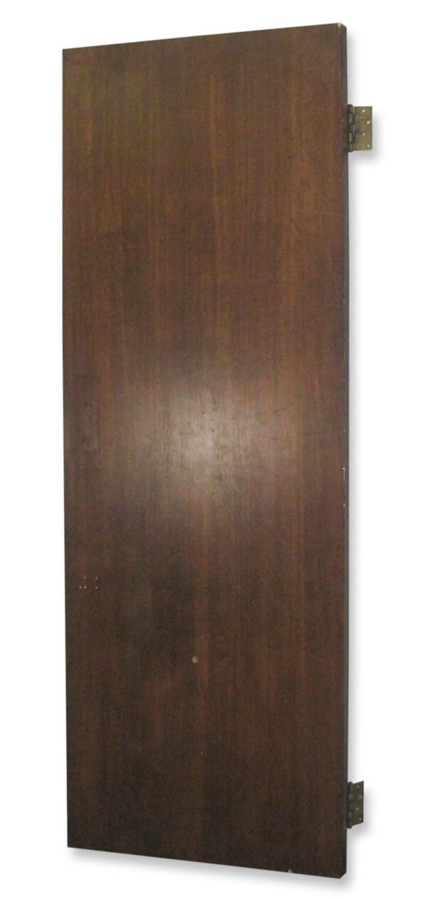 Flat walnut passage door shown at an angle with two visible hinges and no panels.