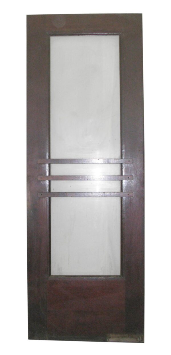 Commercial swinging door with one large vertical glass lite and three horizontal push bars across the center.