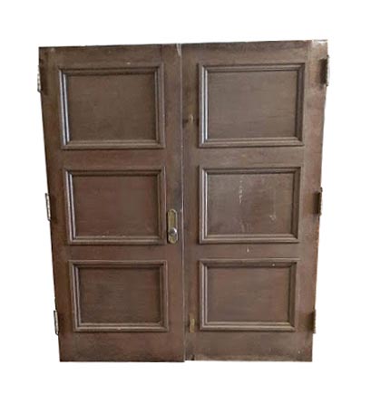Double door with dark wood tone finish, showing three raised panels on each leaf and original hardware attached near the center seam.