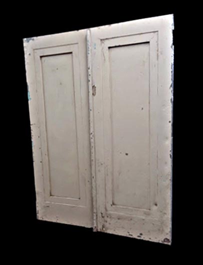 White painted metal double doors with a single vertical panel, shown slightly open and featuring chipped distressed paint.