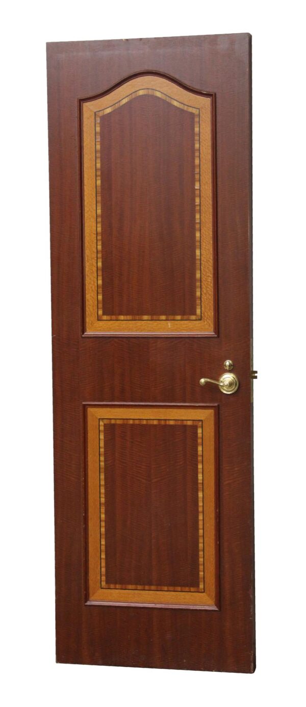 Wooden door with two framed panels outlined in tan and black, shown front on with a brass lever handle on the right side.