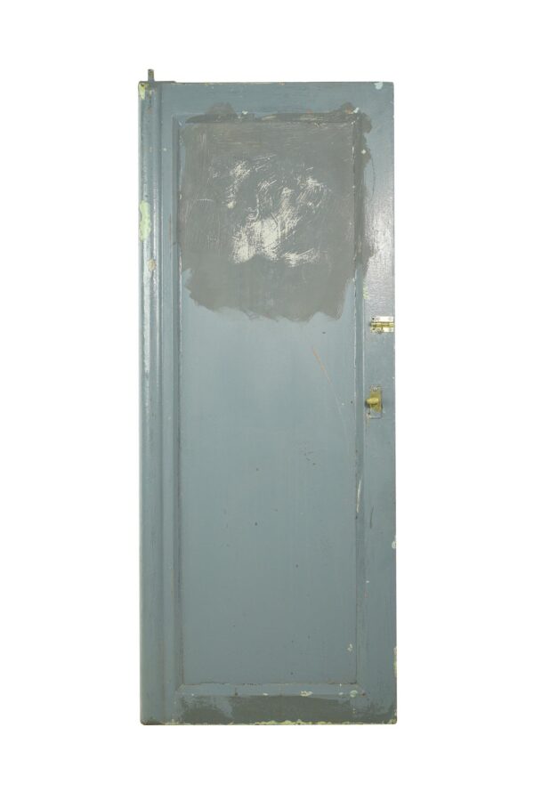 Vintage blue steel commercial door with one vertical panel, chipped paint, rust spots, and original hardware visible on the right edge.