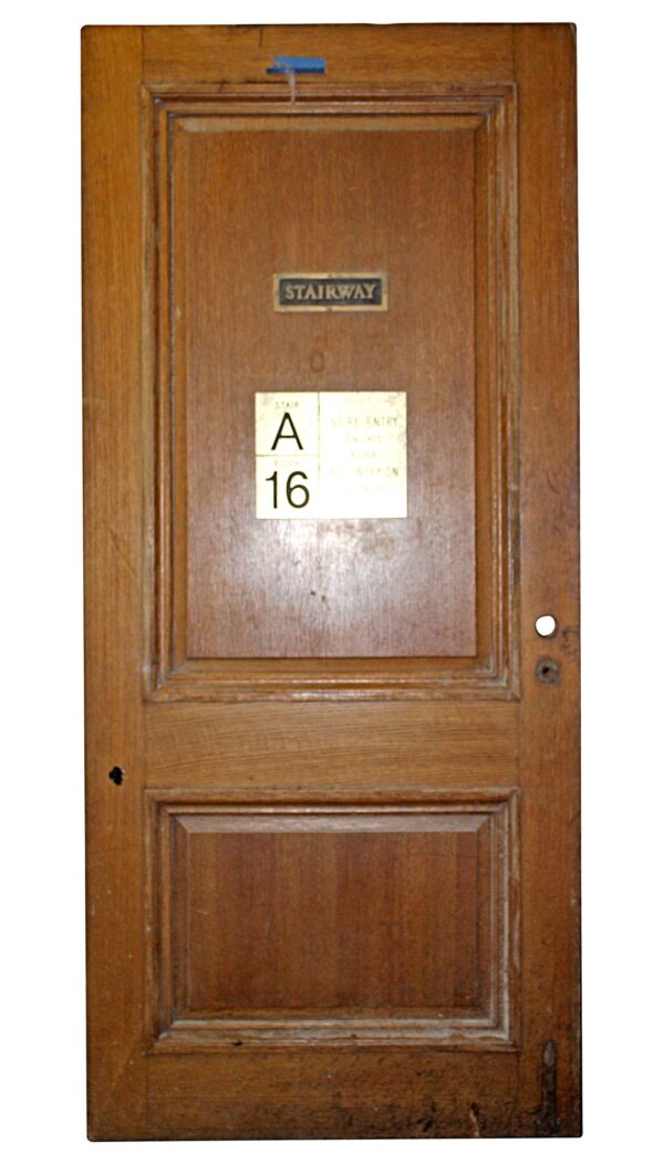 Vintage two-panel oak office door with raised molding and visible stairway and room-number plaques.