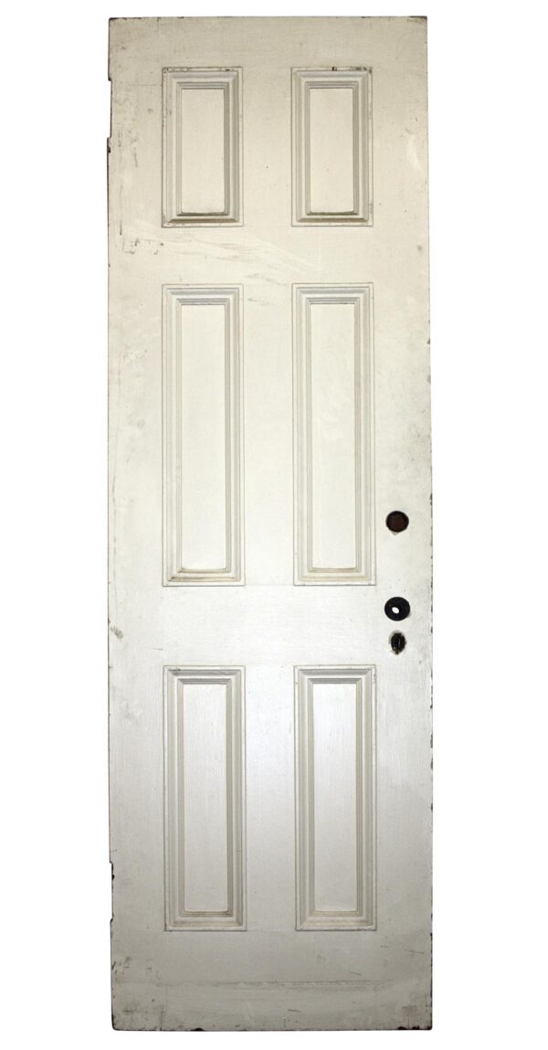 White painted wooden apartment door with six vertical panels and visible hardware holes on the right edge.