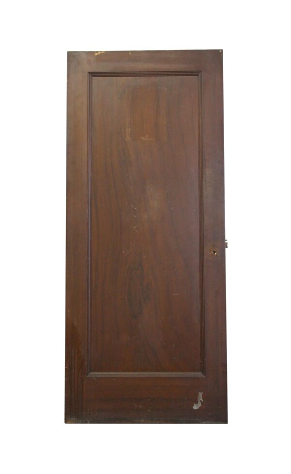 Vintage brown metal fire door with a single full panel and visible hardware opening.