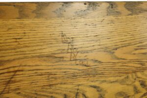 Close-up of a dark wood tone oak bench seat with visible grain and surface wear.