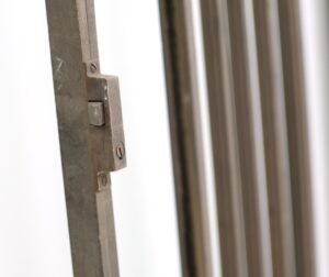 Close-up of a bronze door latch and edge, showing the antique finish and part of the frame.
