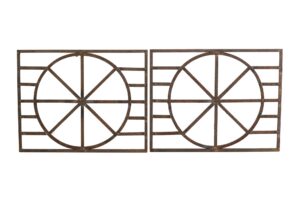 Pair of wrought iron panels with a wheel-like geometric pattern, shown as a rusted matching pair.