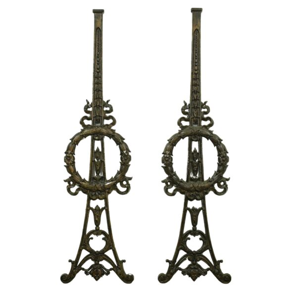 Pair of ornate cast iron spindle pieces with wreath and ribbon motifs, shown as a matching pair.