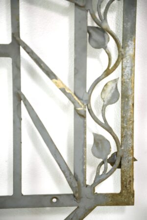 Gray wrought iron wall accent with arched vine and leaf detailing, shown in a close-up view with some rust visible along the right edge and frame.