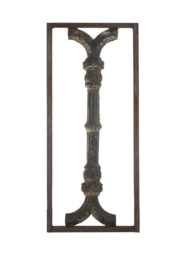 Wrought iron wall panel with a framed decorative baluster and visible rust.