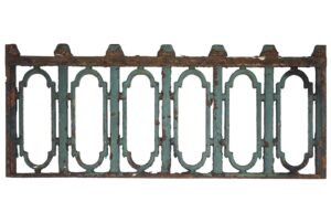 Cast iron balcony guard with six arched sections, chipped teal paint, and visible rust.