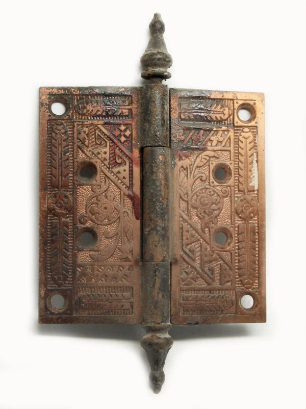 Cast iron antique door hinge with three knuckles, steeple tips, and decorative patterned plates shown front on.