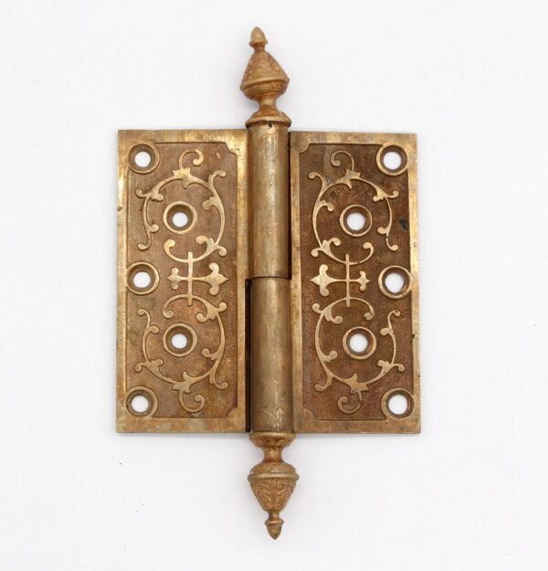 Victorian bronze lift off butt door hinge with steeple tips, decorative scrollwork, and a staggered hole pattern.