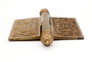 Antique bronze Victorian lift-off butt door hinge shown from the front, with two knuckles, steeple tips, and an ornate staggered hole pattern visible on both leaves.