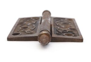 Victorian cast iron lift off butt door hinge with acorn tips and a staggered hole pattern, shown in a close-up view.