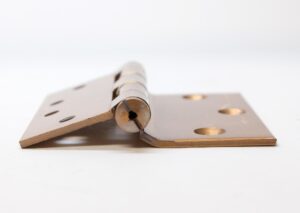 Close-up of a vintage bent door hinge with five knuckles and flat tips, shown open and viewed from the side.
