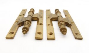 Pair of antique bronze paumelle door hinges with ornate steeple tips and a template hole pattern, shown as a working pair on a white background.
