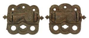 Pair of worn antique door hinges with spring screen design, shown side by side, featuring cast iron construction and multiple mounting holes.