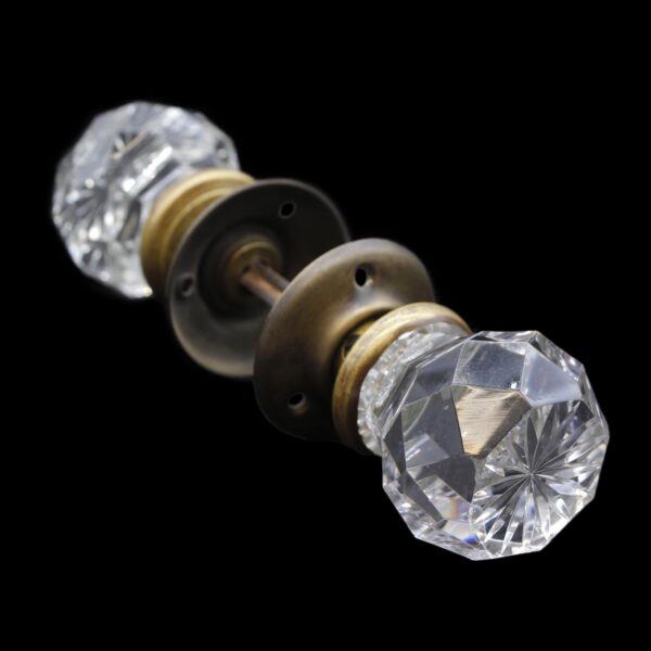 Clear faceted glass doorknob set with etched star centers and antique brass rosettes and shanks, shown in close-up.