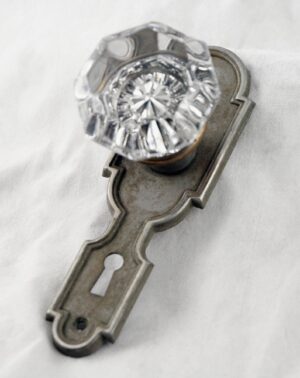 Clear octagon glass door knob with a keyhole back plate in a nickel finish.