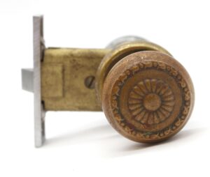 Close-up of a passage door knob set showing a brass knob with a radial floral face and part of the matching brass and nickel plated hardware.