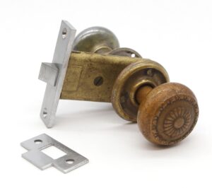 Passage door knob set with one brass-patina knob, one nickel-patina knob, matching rosettes, mortise, strike plate, and spindle.