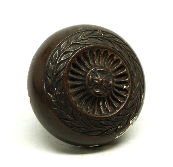 Antique bronze door knob with a concentric floral rosette design and worn surface finish.