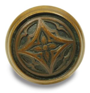 Antique bronze Gothic door knob with a fourfold carved floral pattern shown front on.