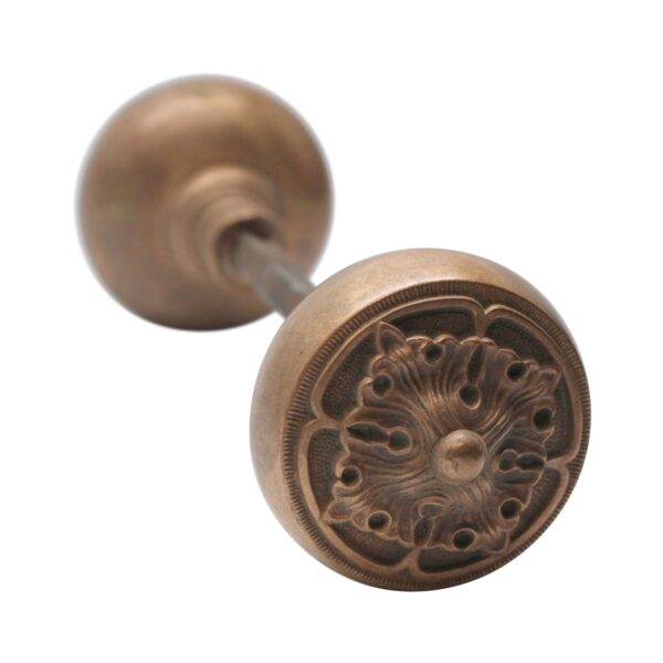 Antique bronze passage door knob pair with spindle, showing a Gothic four-fold rosette design on one knob and a plain back view of the other.