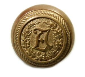 Antique bronze passage door knob with a raised circular emblem and a decorative letter in the center.