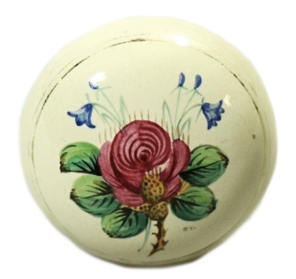 White porcelain door knob with a hand-painted pink flower, blue blossoms, and green leaves, shown front on with visible surface wear.