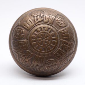 Antique bronze door knob with a six-fold engraved pattern and worn surface.