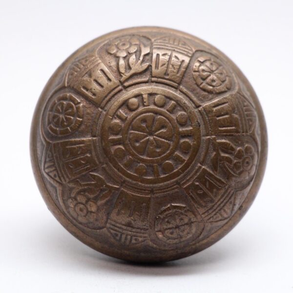 Antique bronze door knob with a six-fold engraved pattern and worn surface.