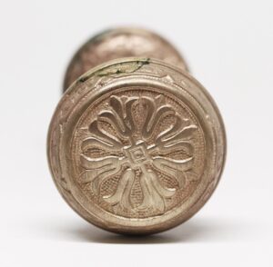Close-up of a brass door knob with a four-petal floral rosette design and visible surface wear.