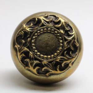 Romanesque bronze door knob with a swirl pattern and beaded center detail.