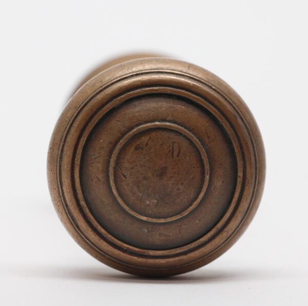 Close-up of a cast bronze doorknob with concentric ring detailing and an antique bronze finish.