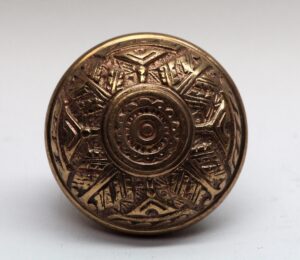 Front view of a patterned bronze door knob with a polished finish and circular center detail.