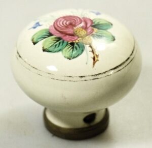 Hand-painted ceramic door knob with a pink flower and green leaves on a white base, shown in close-up with the mounting stem visible.