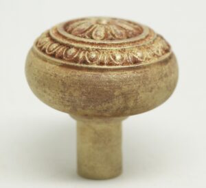 Close-up of an antique Victorian bronze door knob with a floral and egg-and-dart top and a worn finish.