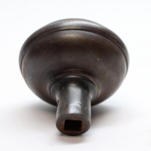 Antique cast iron passage door knob shown from the back, with a square spindle opening and a worn black finish.