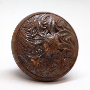 Close-up of a cast iron door knob with a raised swirl design and visible surface wear.