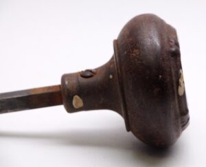 Close-up of an antique cast iron passage door knob with a dark black finish and visible surface wear.