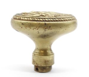Victorian bronze door knob with an oval top, ornate border, and worn antique finish shown in close-up.