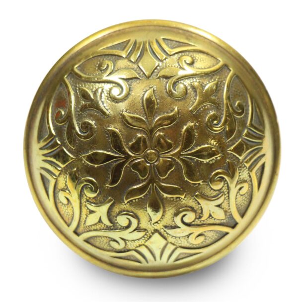 Ornate round bronze door knob with a four-fold floral and scroll design, shown in close-up front view.