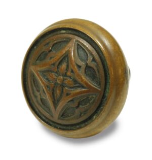 Antique bronze Gothic passage door knob with a fourfold carved pattern shown in close-up.
