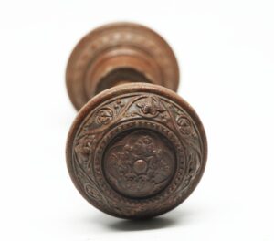 Victorian wood door knob with a concentric floral and scroll carving, shown from the end.